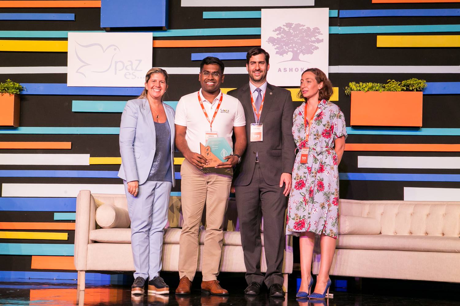 Group of Orang Asli community members posing together with Saora+ team in a village clearing surrounded by tropical forest