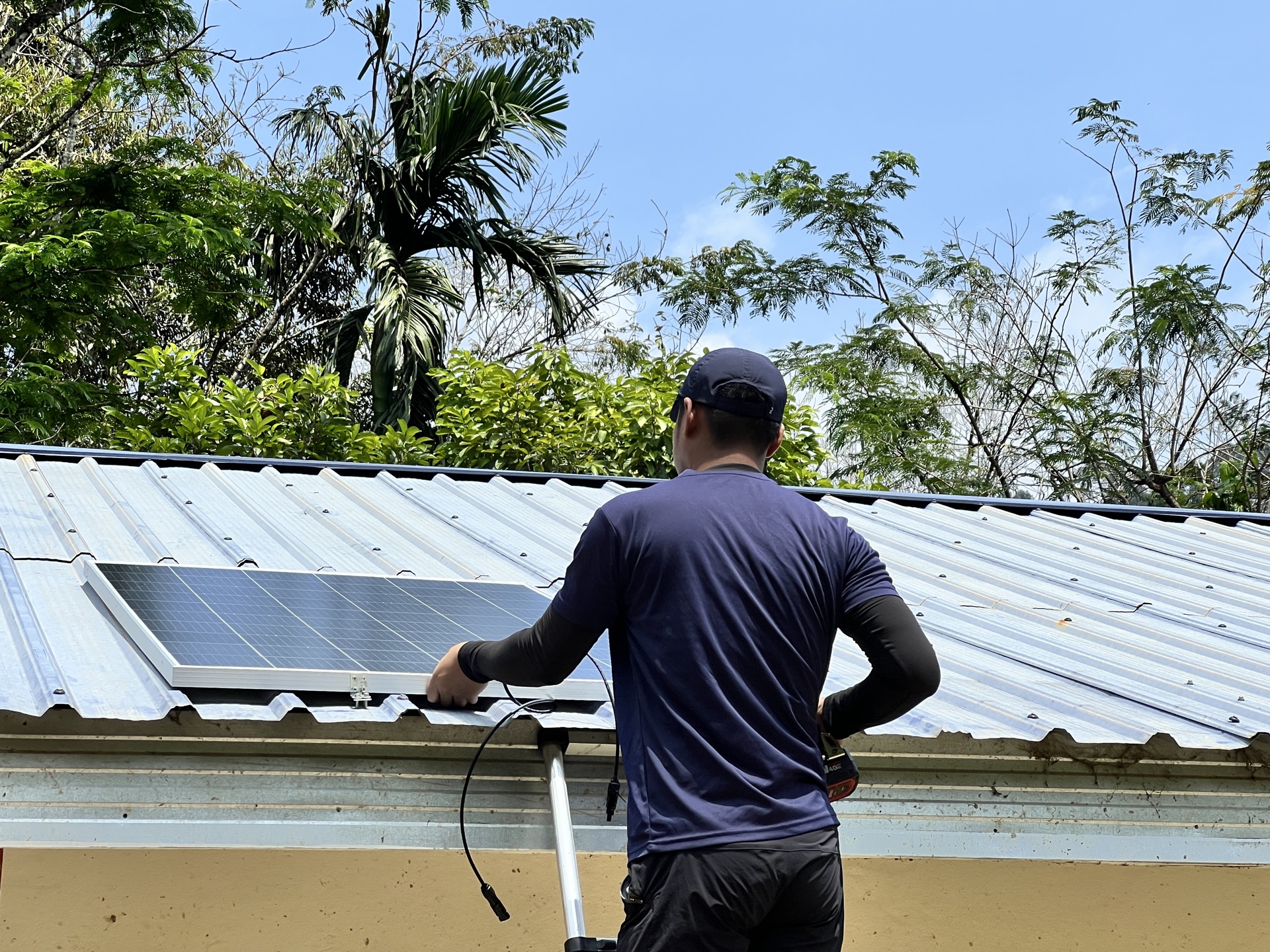 Solar panel array mounted on the roof of an Orang Asli communal hall, providing renewable energy to a remote village