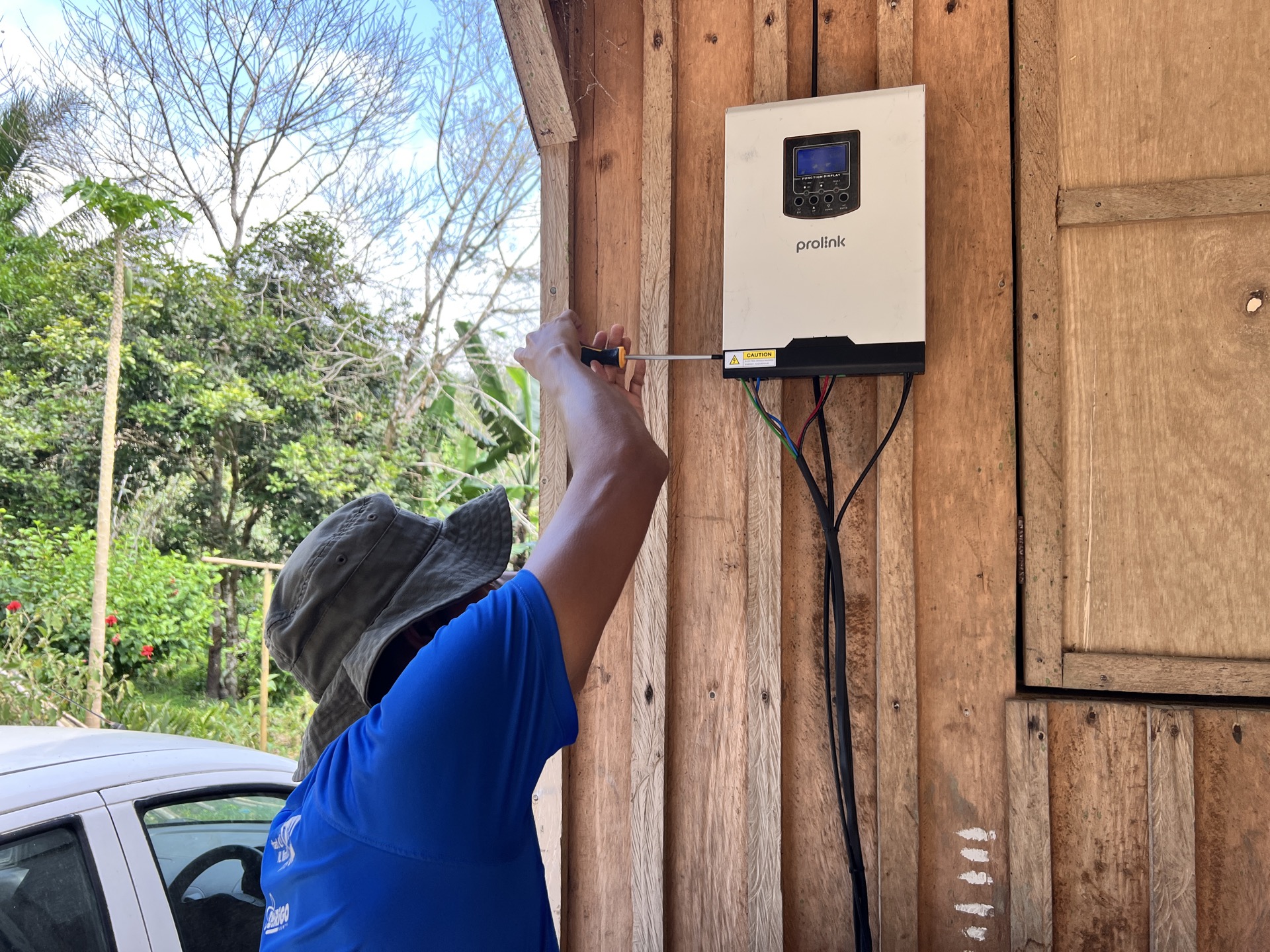 Saora+ technicians installing solar panels on a village learning centre, working alongside community members