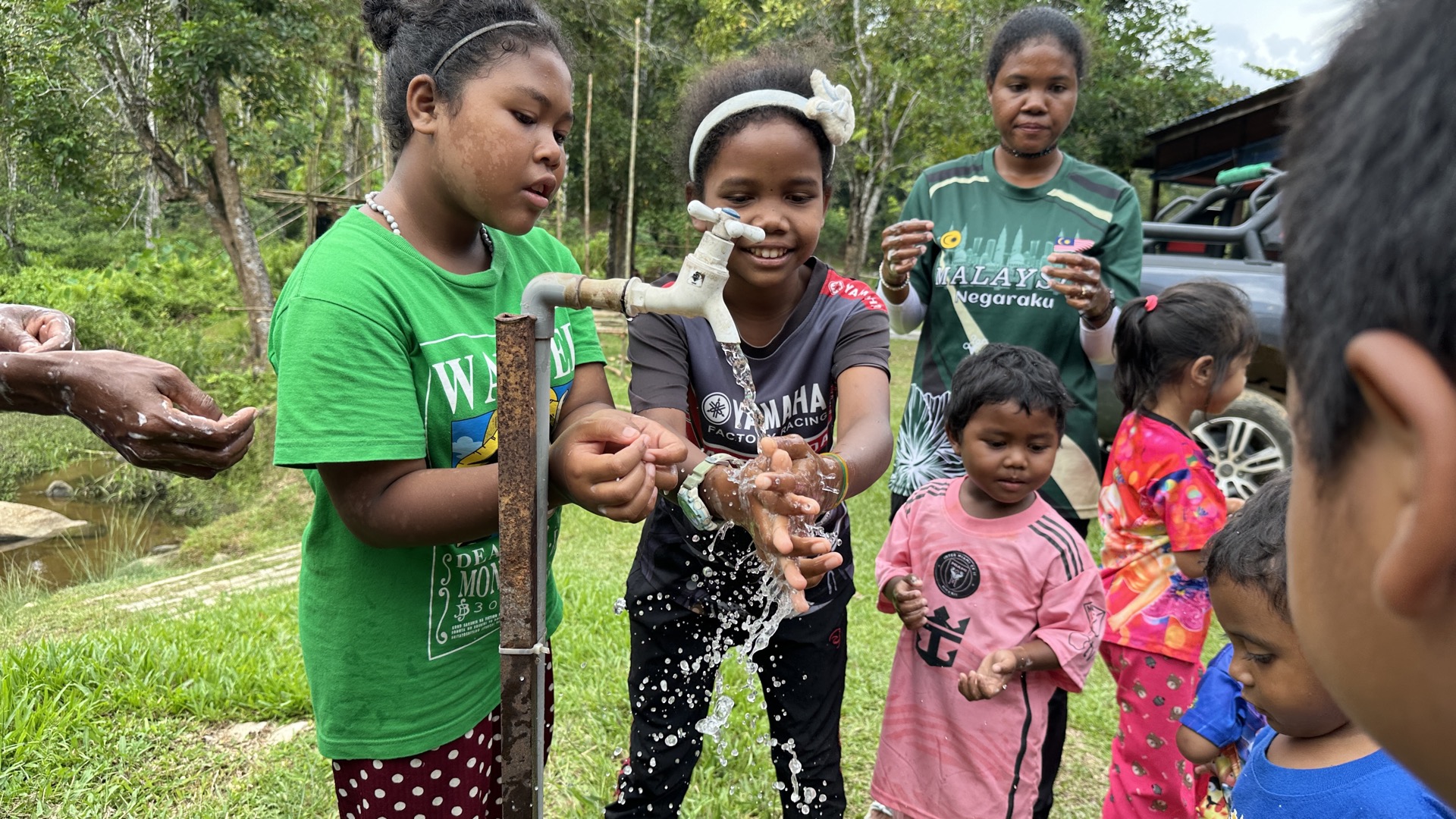 Community members helping construct a clean water supply point, carrying materials through the rainforest terrain